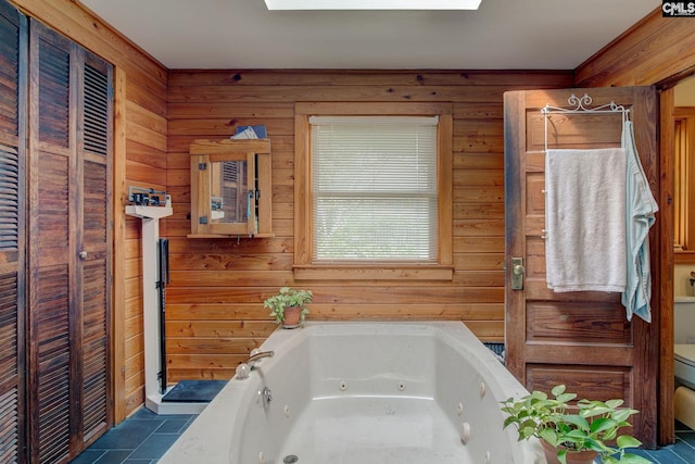 bathroom featuring a washtub, wooden walls, and toilet