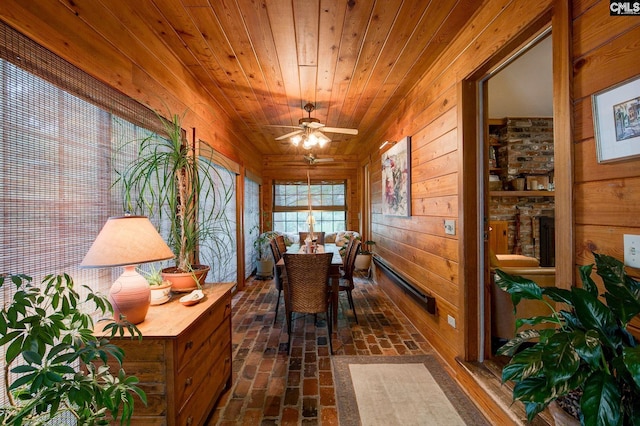 office featuring ceiling fan, a stone fireplace, wooden walls, and wooden ceiling