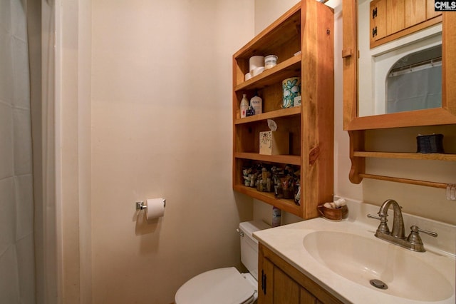 bathroom with walk in shower, vanity, and toilet