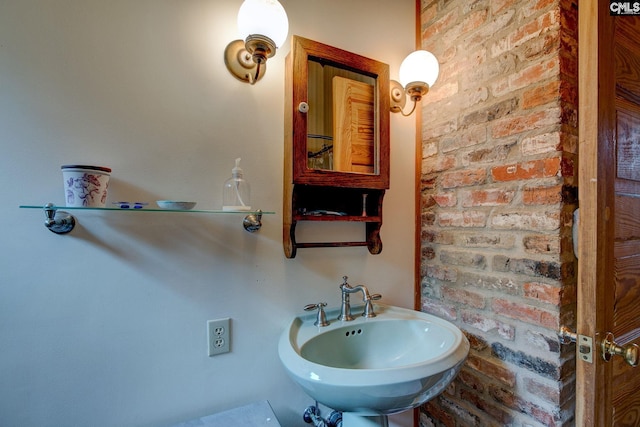 bathroom featuring sink and brick wall