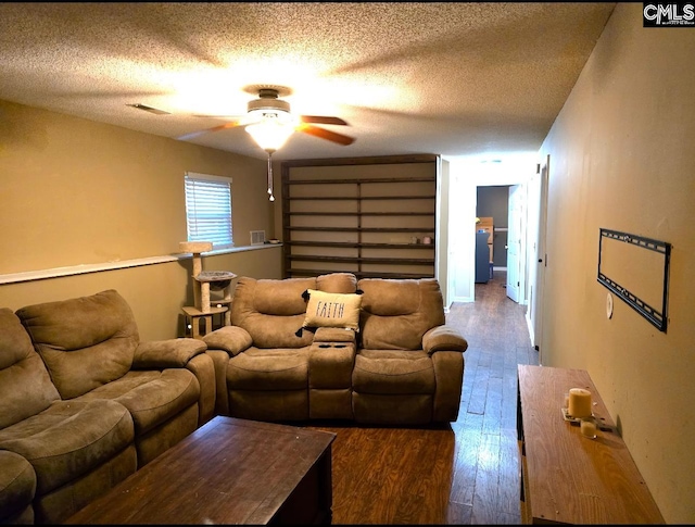 living room featuring a textured ceiling, dark wood-type flooring, and ceiling fan