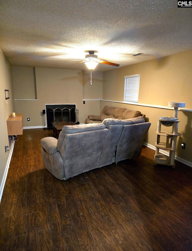 living room featuring ceiling fan, dark hardwood / wood-style floors, and a textured ceiling