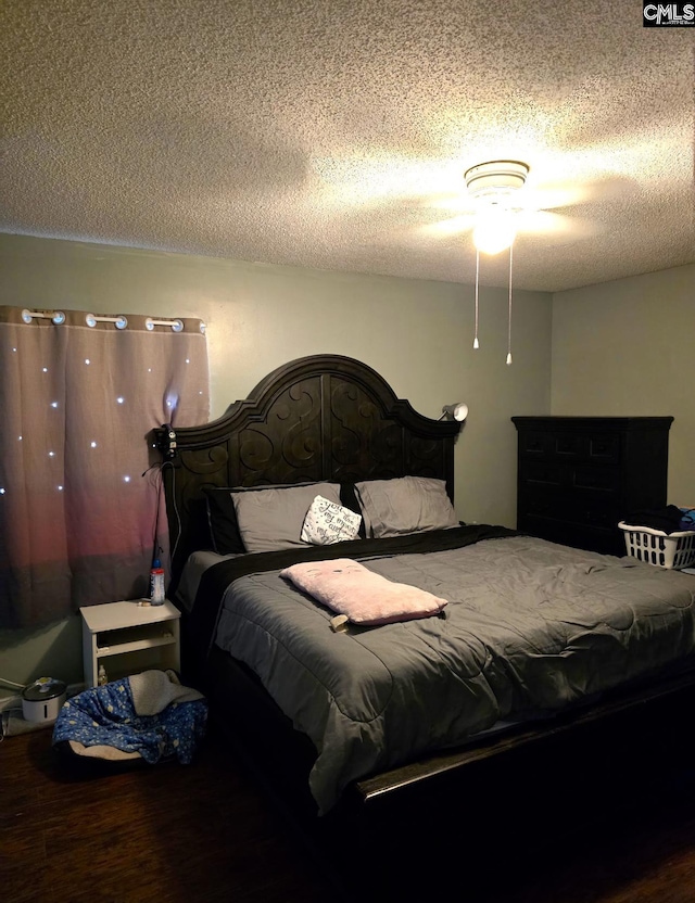 bedroom with ceiling fan, a textured ceiling, and hardwood / wood-style floors