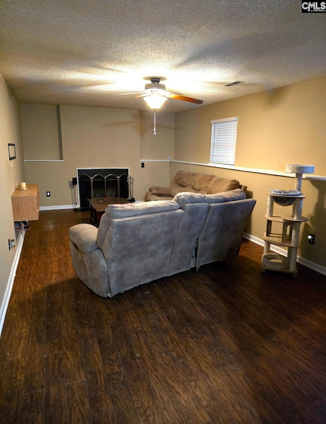 living room with ceiling fan, a textured ceiling, and dark wood-type flooring