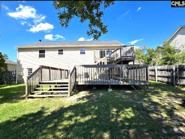 rear view of house with a wooden deck and a yard