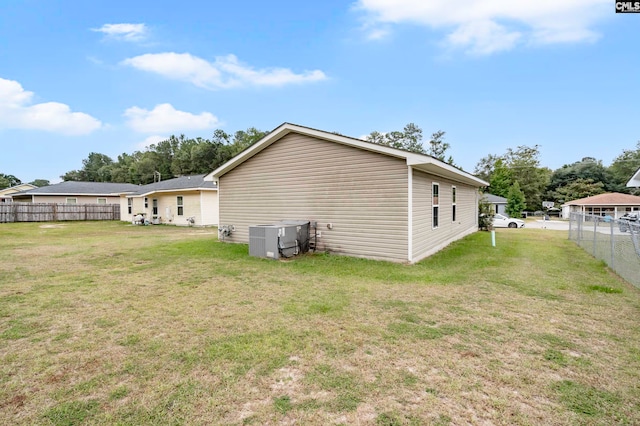 rear view of property featuring central AC and a yard