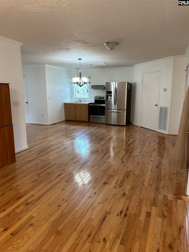 interior space featuring appliances with stainless steel finishes, exhaust hood, a textured ceiling, light hardwood / wood-style flooring, and a notable chandelier