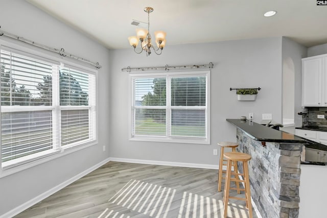 unfurnished dining area featuring a notable chandelier and light hardwood / wood-style floors