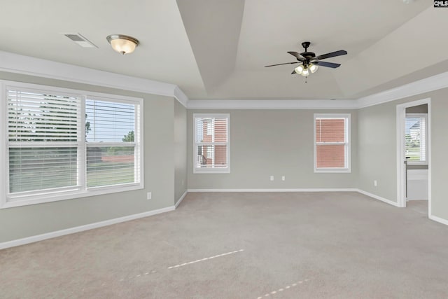 carpeted empty room featuring ceiling fan, a tray ceiling, and plenty of natural light