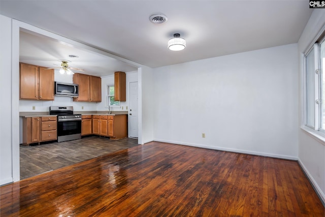 kitchen with ceiling fan, stainless steel appliances, dark wood-type flooring, and a healthy amount of sunlight