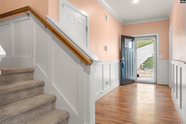 foyer entrance with light hardwood / wood-style flooring and crown molding