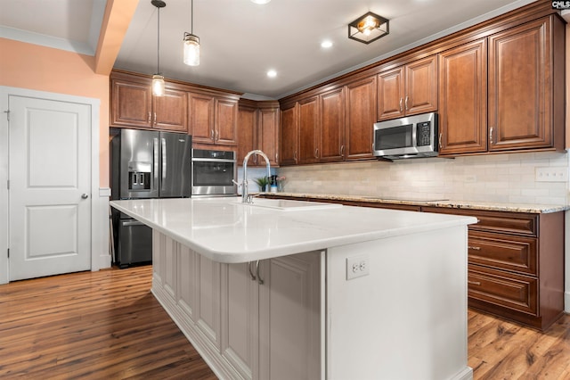 kitchen featuring an island with sink, light wood-type flooring, stainless steel appliances, sink, and a breakfast bar area