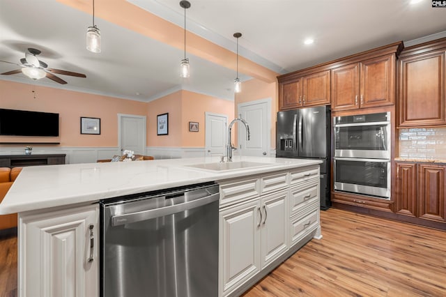 kitchen featuring sink, a kitchen island with sink, backsplash, appliances with stainless steel finishes, and light hardwood / wood-style floors