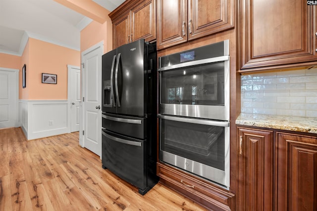 kitchen featuring light stone countertops, stainless steel double oven, black refrigerator with ice dispenser, light hardwood / wood-style flooring, and backsplash