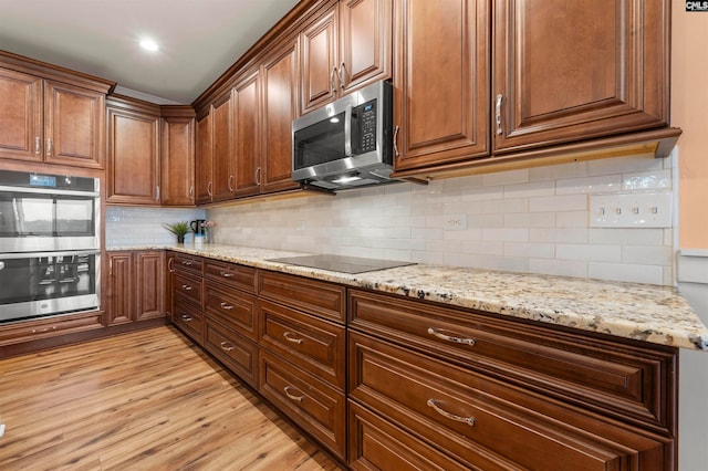 kitchen featuring light stone countertops, stainless steel appliances, backsplash, and light hardwood / wood-style floors