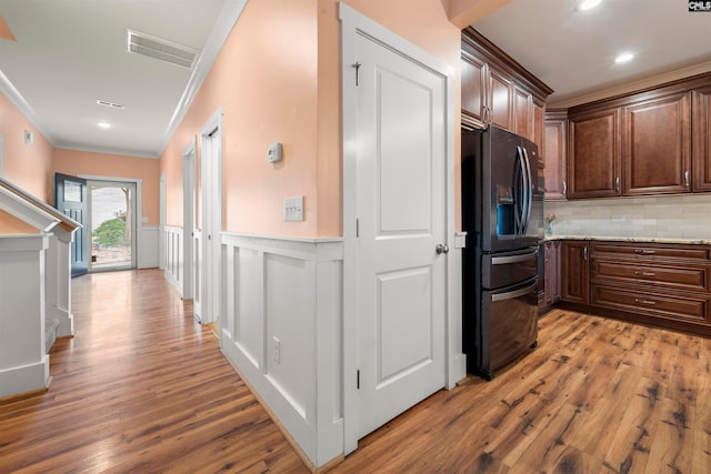 hallway with light wood-type flooring and ornamental molding