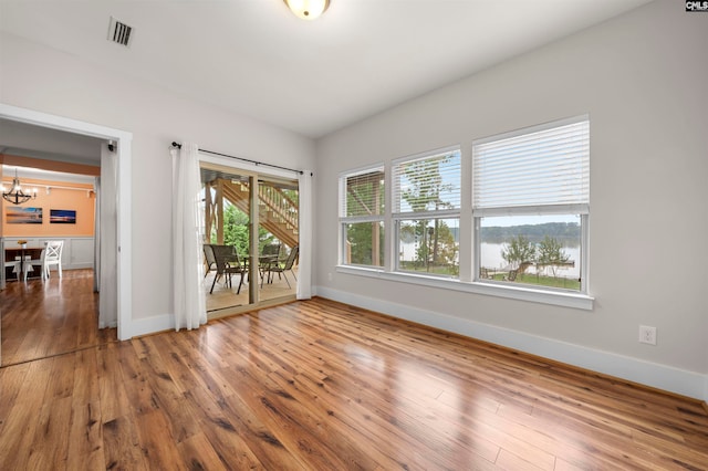 empty room featuring a notable chandelier and wood-type flooring