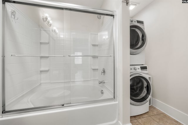 bathroom with stacked washing maching and dryer, tile patterned floors, and shower / bath combination with glass door