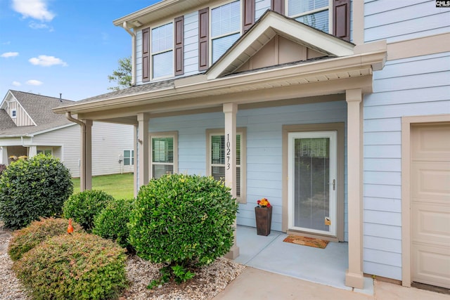 doorway to property with covered porch and a garage