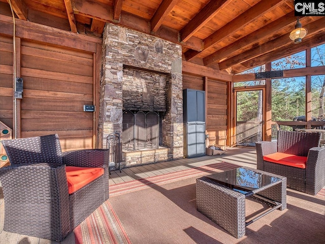 sunroom with a stone fireplace, lofted ceiling with beams, and wooden ceiling