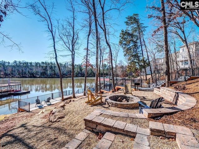 view of patio featuring a water view, a dock, and a fire pit