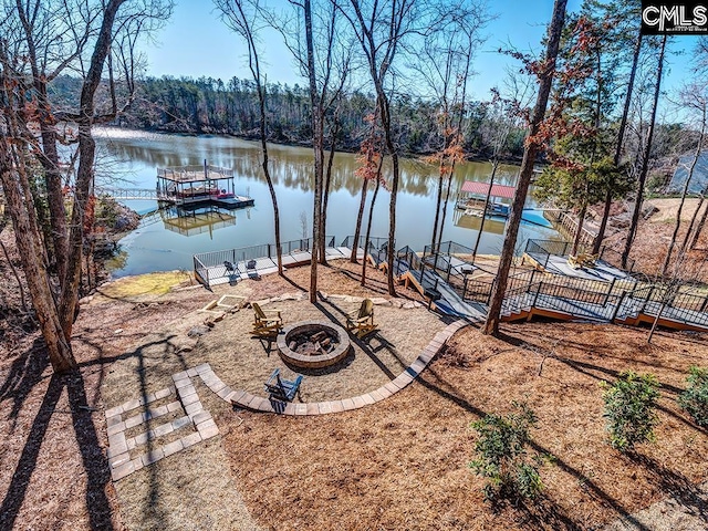 exterior space featuring a water view, a fire pit, and a dock