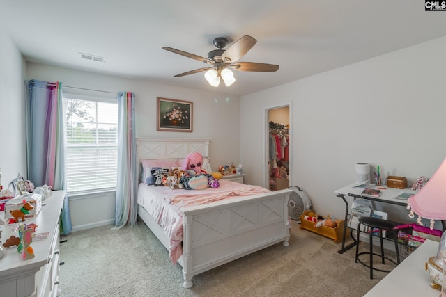 bedroom with a spacious closet, light carpet, ceiling fan, and a closet