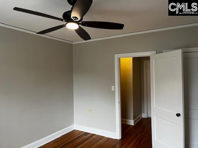 spare room with ceiling fan, dark wood-type flooring, and crown molding