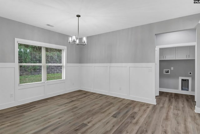 unfurnished dining area featuring an inviting chandelier and hardwood / wood-style flooring