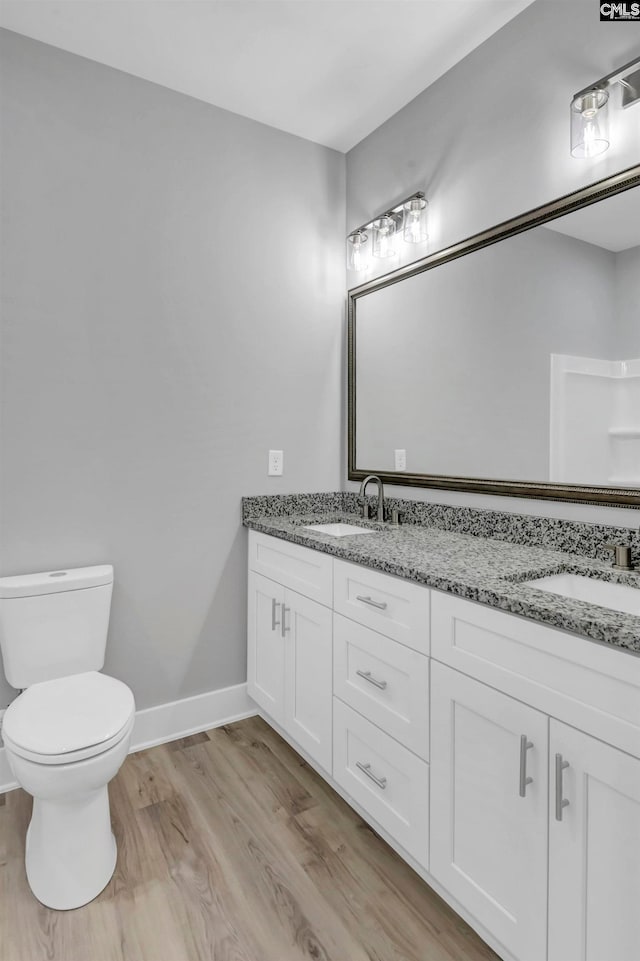 bathroom featuring wood-type flooring, vanity, and toilet