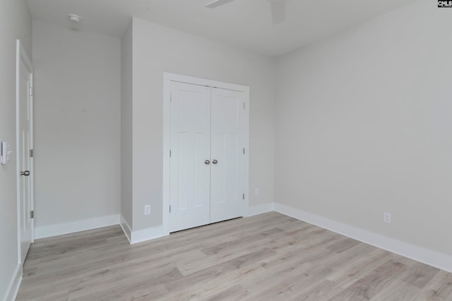 unfurnished bedroom featuring light hardwood / wood-style flooring, a closet, and ceiling fan