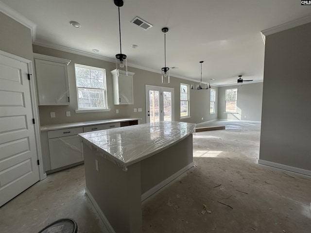 kitchen with baseboards, visible vents, white cabinets, a center island, and hanging light fixtures