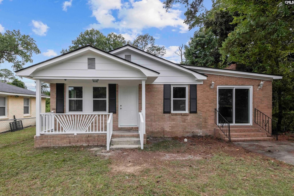 bungalow-style home featuring covered porch and a front yard