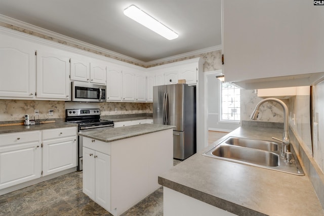 kitchen with sink, a center island, ornamental molding, appliances with stainless steel finishes, and white cabinets