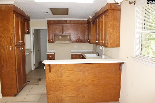 kitchen featuring kitchen peninsula, ornamental molding, sink, and light tile patterned floors