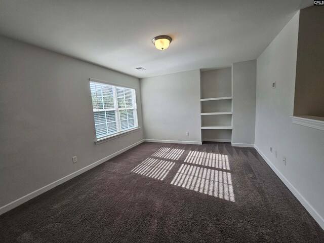 spare room featuring dark colored carpet