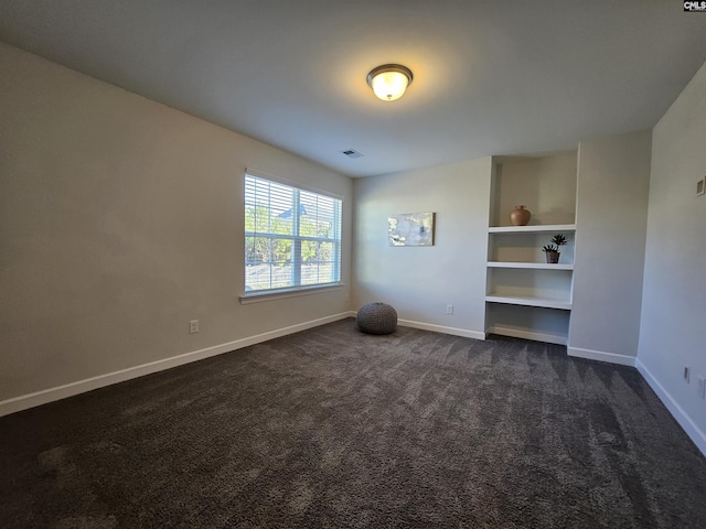 empty room featuring built in shelves and dark carpet