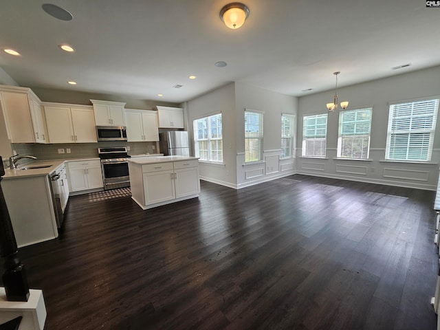 kitchen featuring white cabinetry, sink, pendant lighting, a kitchen island, and appliances with stainless steel finishes