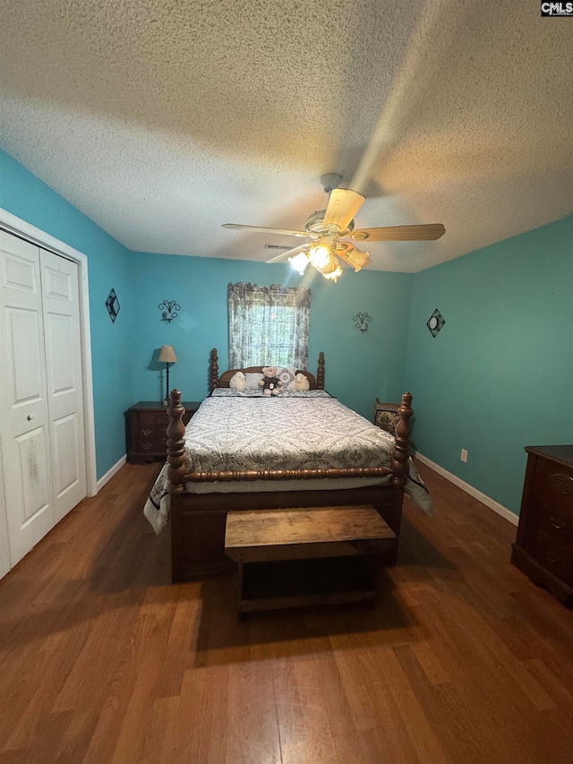 bedroom featuring a textured ceiling, dark wood-type flooring, ceiling fan, and a closet