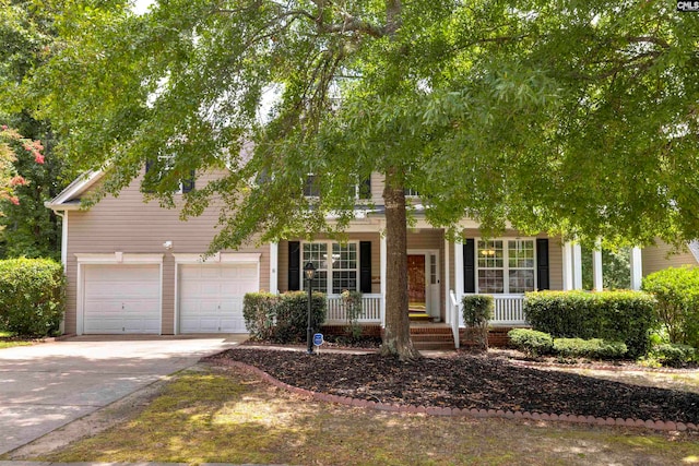 view of property hidden behind natural elements featuring a porch and a garage