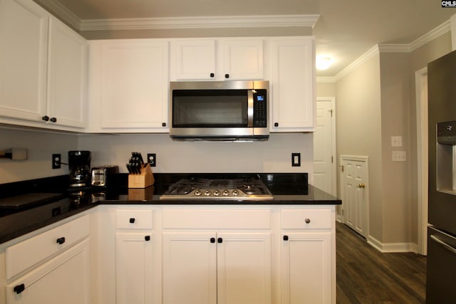 kitchen with stainless steel appliances, white cabinets, crown molding, and dark hardwood / wood-style flooring