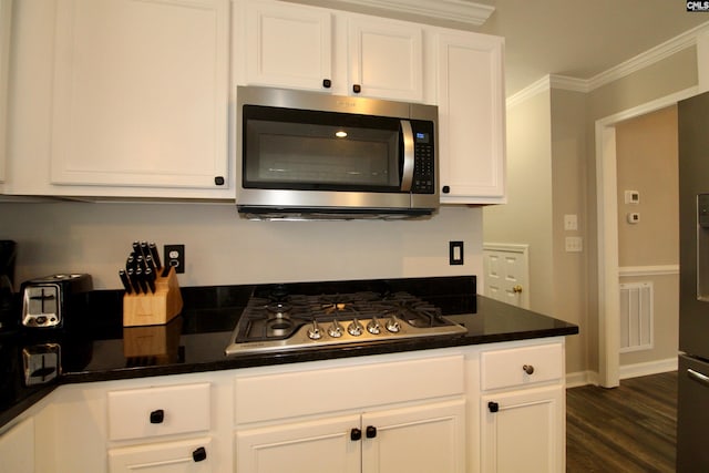 kitchen with ornamental molding, dark hardwood / wood-style floors, stainless steel appliances, and white cabinets