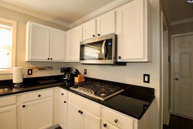 kitchen featuring appliances with stainless steel finishes, ornamental molding, white cabinetry, and dark countertops