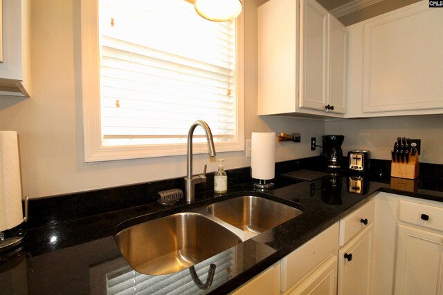 kitchen with dark stone counters, a healthy amount of sunlight, white cabinetry, and sink