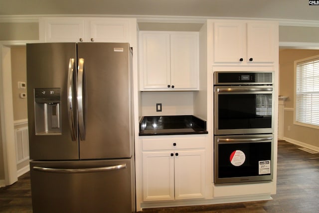 kitchen with stainless steel appliances, white cabinetry, dark wood-type flooring, and crown molding