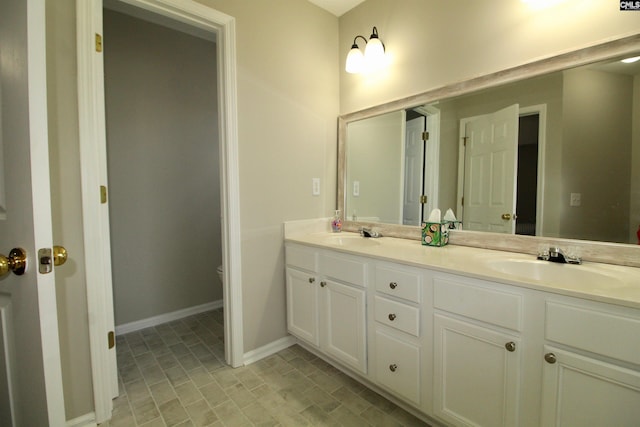 full bath with double vanity, baseboards, and toilet