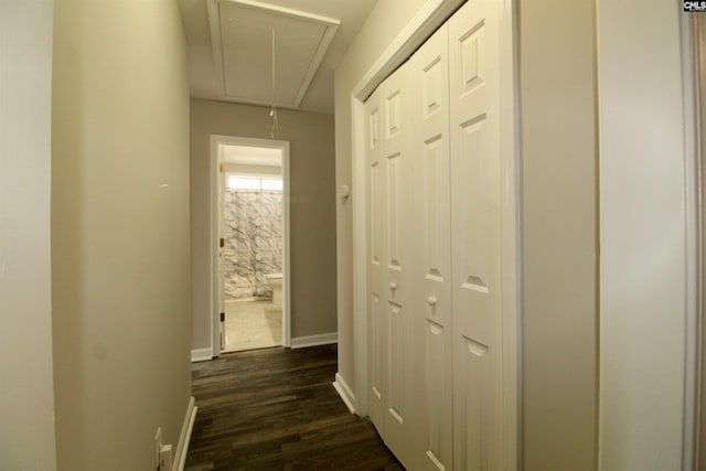 hallway featuring attic access, dark wood-style flooring, and baseboards