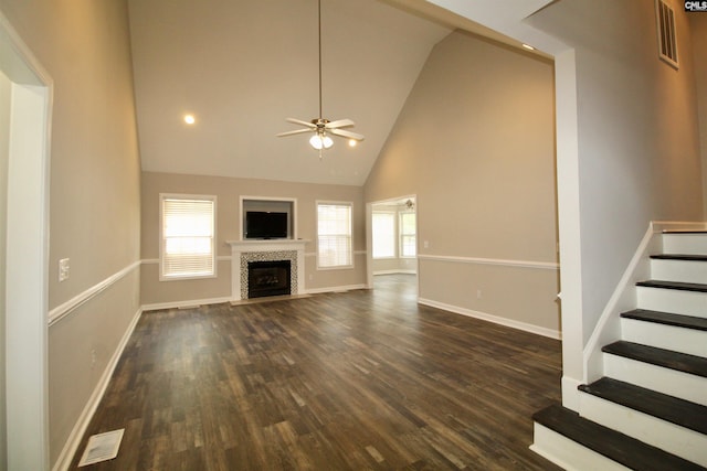 unfurnished living room with a ceiling fan, high vaulted ceiling, dark wood-style floors, baseboards, and stairway