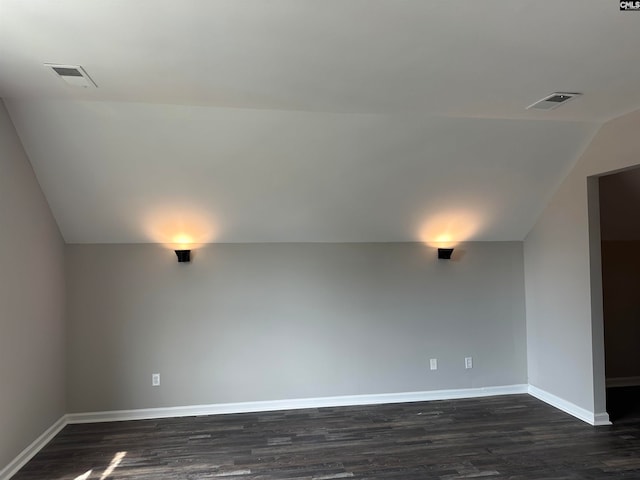 spare room with dark hardwood / wood-style floors and vaulted ceiling