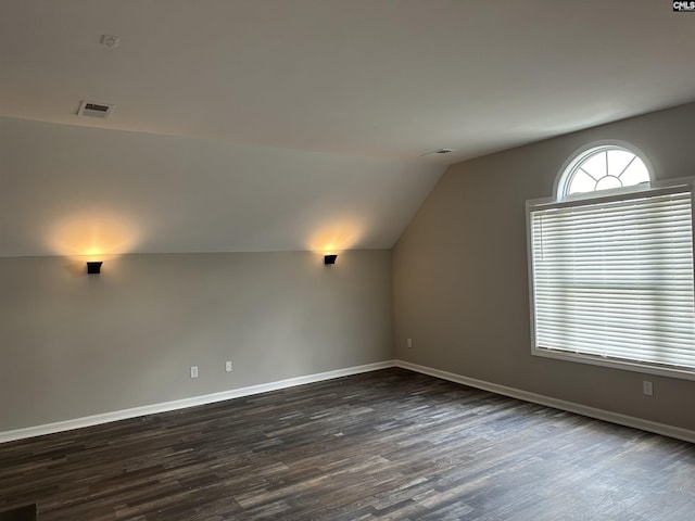 bonus room featuring dark wood-type flooring, lofted ceiling, and baseboards